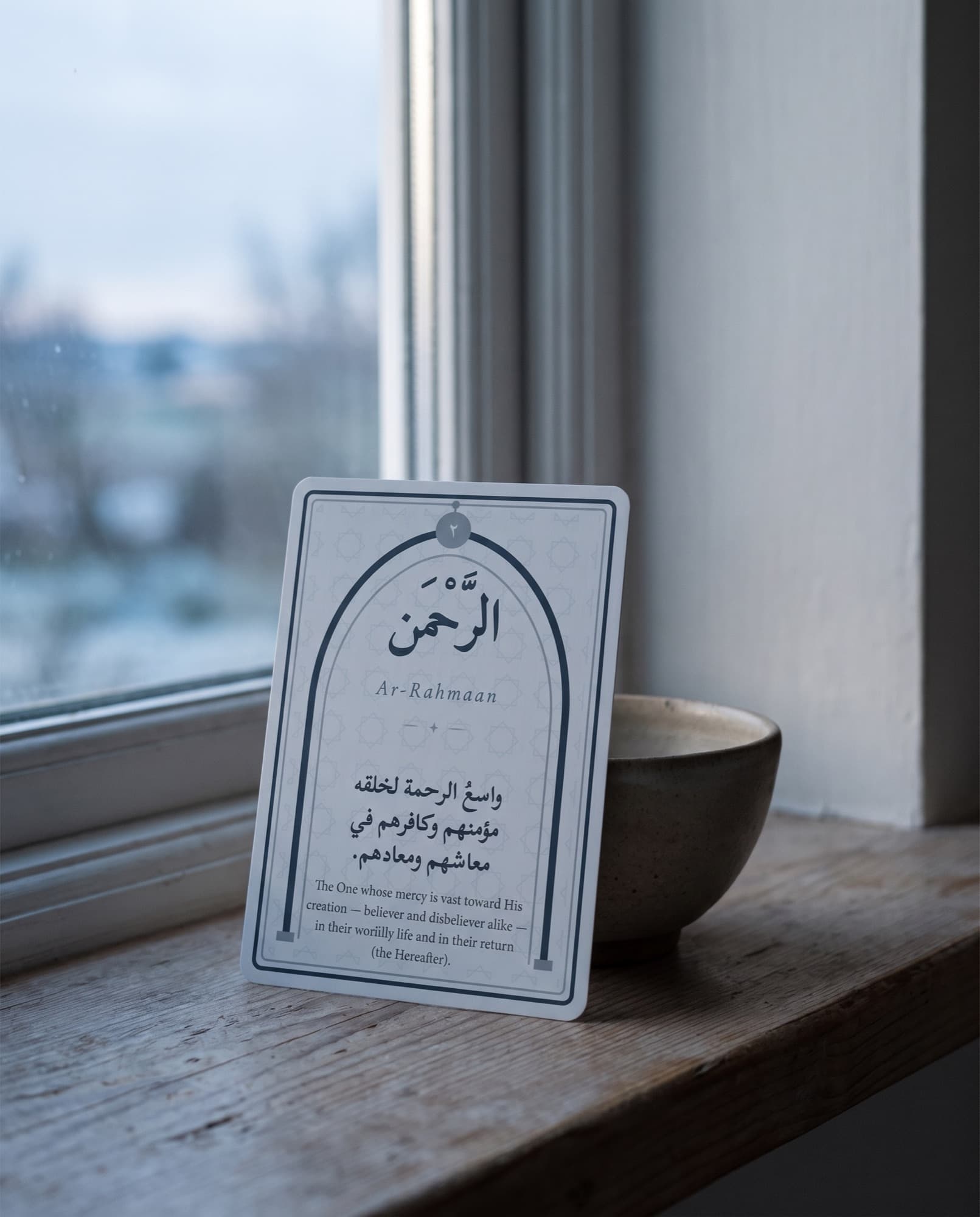 A card in a small bowl by a window at dawn